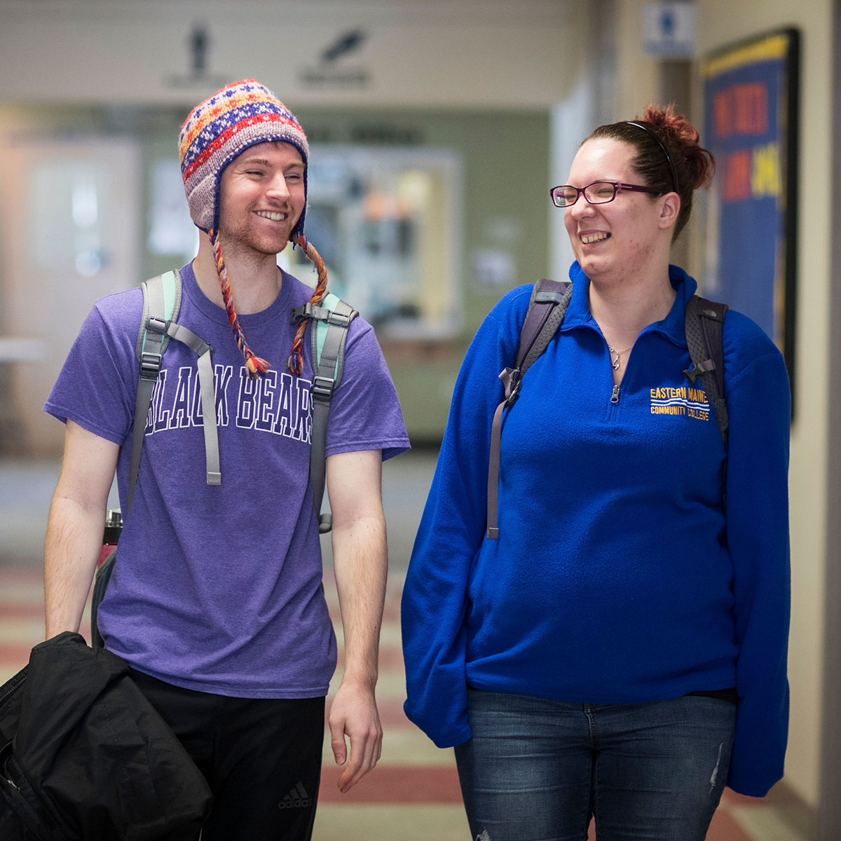 Two students walking down hallway.