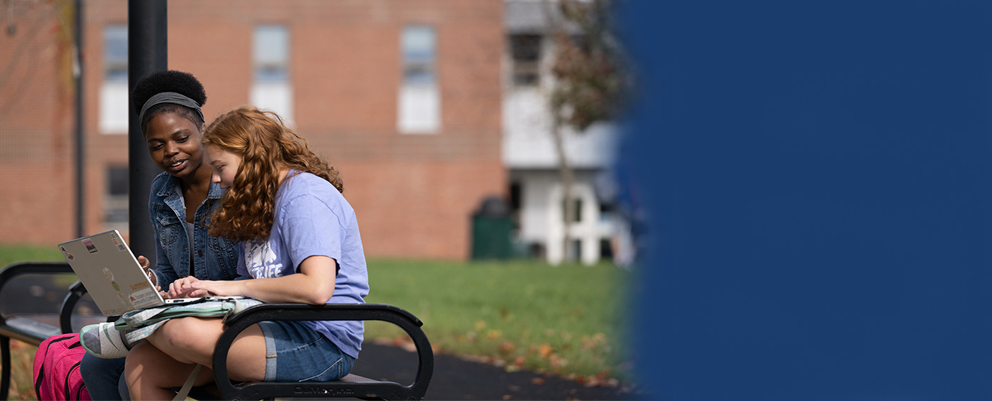 Students sitting on a bench outside.