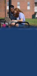 Students sitting outside on a bench.